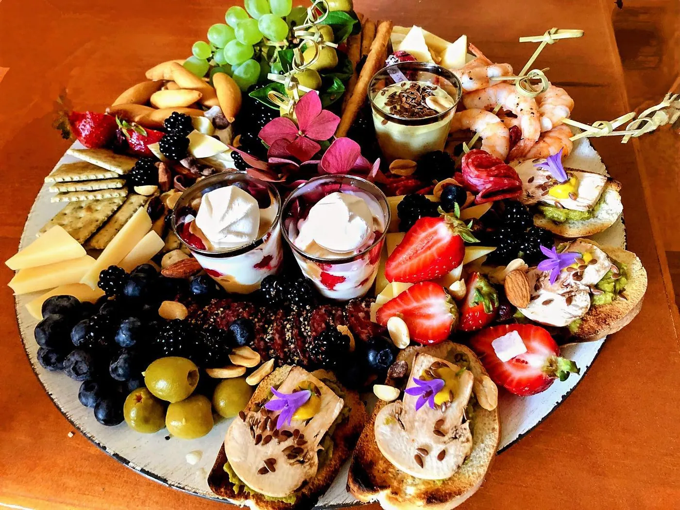 Tabla con frutas, aceitunas y flores comestibles